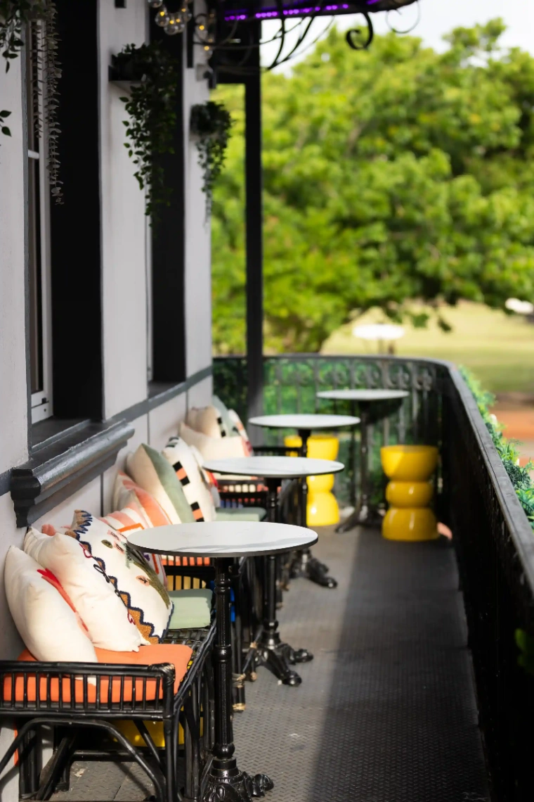 Terrasse ombragée d'un restaurant en Martinique avec fauteuils confortables et vue sur un jardin tropical.