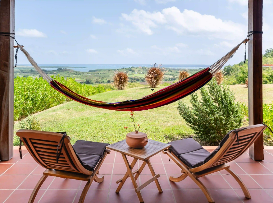 Terrasse avec hamac et vue panoramique sur la mer et la campagne en Martinique.