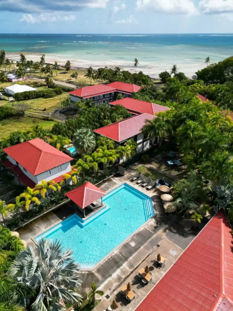 Vue aérienne de la piscine du Village de la Pointe avec la mer et les palmiers en arrière-plan
