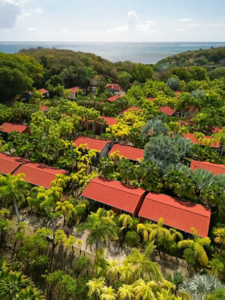 Cottages aux toits rouges entourés d'un jardin tropical au Village de la Pointe en Martinique